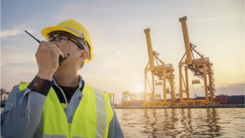 Man holding a walkie-talkie at a port
