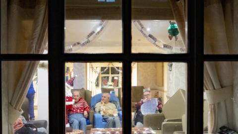 Residents of a care home in Liverpool seen through a window