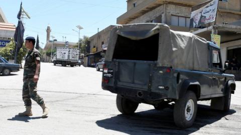 A Lebanese army soldier walks near a military vehicle at the entrance of the border town of Arsal, in eastern Bekaa Valley, Lebanon June 30, 2017