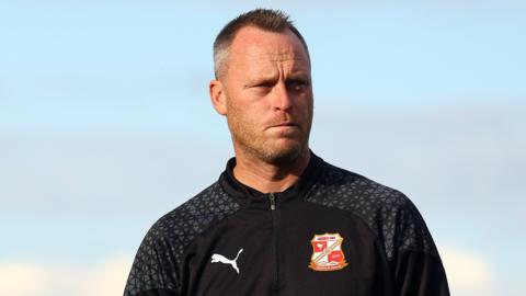 Swindon manager Michael Flynn walks on the pitch before kick-off of a game at home