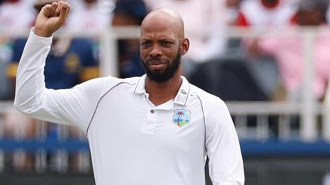 Roston Chase holds up his right arm with a clenched fist