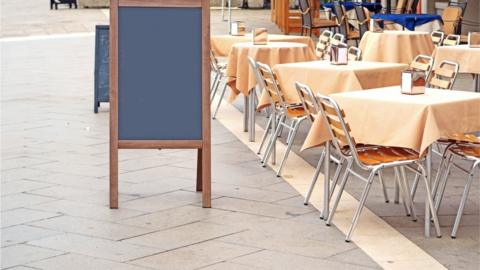 An advertising board on a pavement outside a cafe