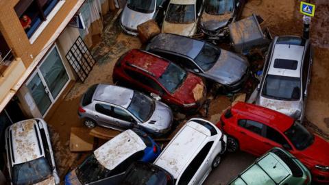 A man looks from his window at piled cars after heavy rains in Sedavi, in Valencia