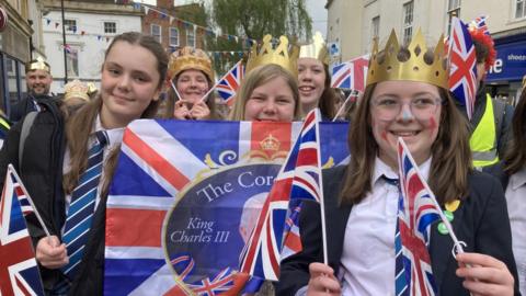 Children participating in the parade with flags and crowns