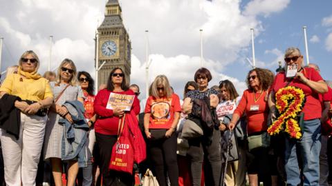 People affected by the infected blood scandal hold a minute silence during a vigil in Parliament Square on May 19, 2024
