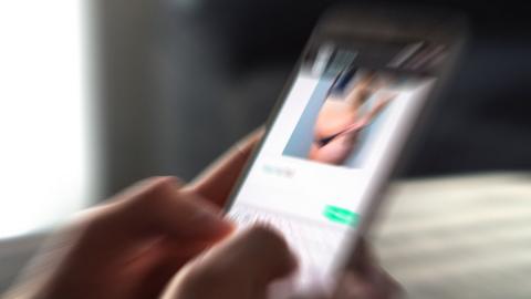 A close-up of a phone with a blurred image of a woman in underwear