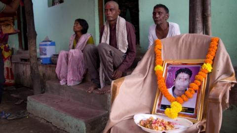 Pravin Soyam's family sit next to a photograph of him
