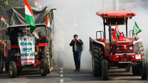 A farmer covers his face to protect himself from tear gas