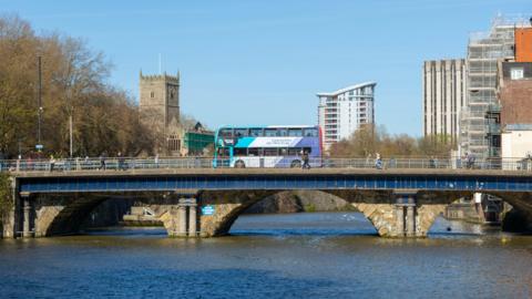 A bus travels over a bridge with a river running beneath it