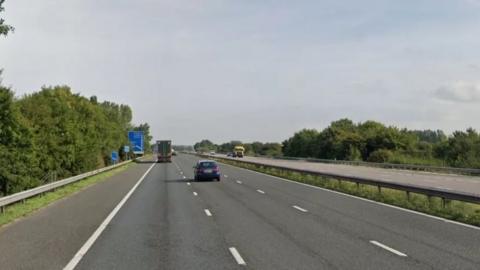 A stretch of the M5 motorway with one car and one HGV lorry in separate lanes.