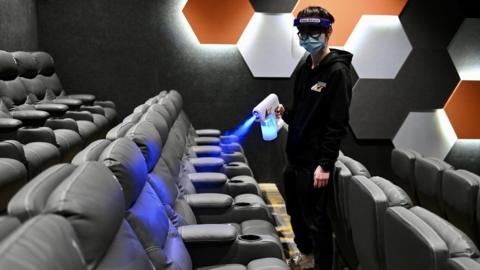 An employee sprays disinfectant to seats at a cinema during its reopening on February 18, 2021 in Hong Kong, China.