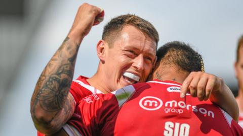 Salford Red Devils player Deon Cross celebrates a try by teammate Ken Sio