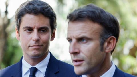 French Education and Youth Minister Gabriel Attal (L) looks at France's President Emmanuel Macron (R) addressing the audience at the 'lycée professionnel de l'Argensol' or Argensol vocational school during his visit of the school in Orange, Southeastern France on September 1, 2023