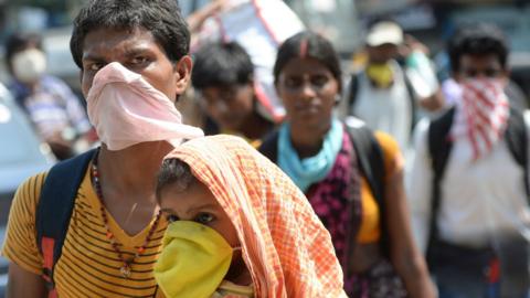 A stranded migrant labourer with his infant walks in Bihar