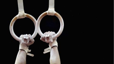 close up of gymnast hands holding on to rings