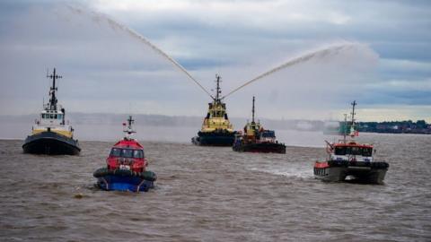 River tugs perform Fleur De Lis, (spraying of water from their fire cannons) as vessels gather on the River Mersey in Liverpool