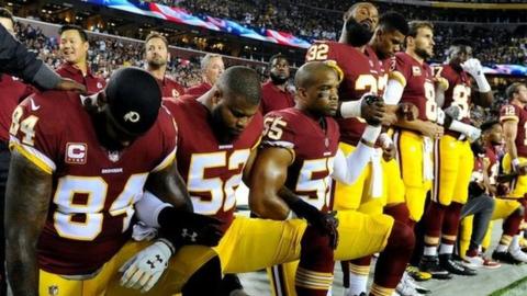 Members of the Washington Redskins kneel during the playing of the national anthem.