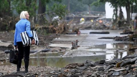 A woman carries bags in a devastated street after the floods caused major damage in Bad Neuenahr-Ahrweiler, western Germany, on July 16, 2021.