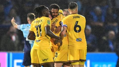 Sutton players hug and celebrate their win against Wycombe