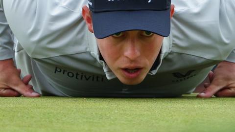 Matthew Fitzpatrick laying on the green to study a putt at the 2022 US Open