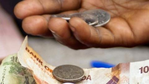 A hand holding Ugandan currency