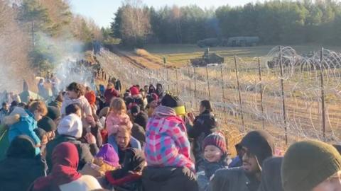 Migrants gather near a barbed wire fence on the Poland - Belarus border in Grodno District, Belarus