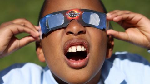 Adrian Plaza, 9, of Queens, tests his eclipse glasses ahead of a partial solar eclipse, where the moon will partially blot out the sun, at New York Hall of Science in Queens borough, New York City, U.S., April 8, 2024.