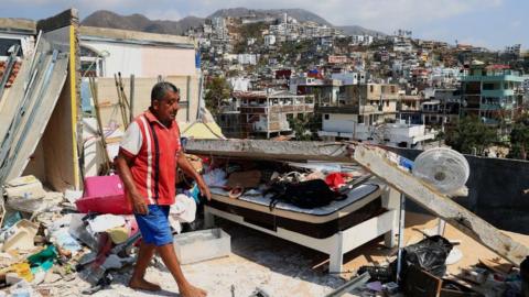 A person clears his house of debris in an area affected by Hur