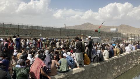 Afghans crowd outside the secure compound