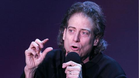 Richard Lewis speaks into a microphone
