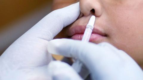 Child being given nasal flu vaccine