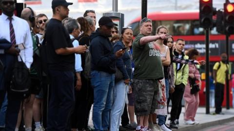 People queue for buses at Victoria Station in London, Britain, 21 June 2022