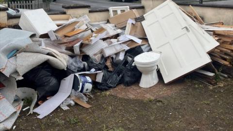 Doors, debris and a toilet thrown into a pile of rubbish on the ground
