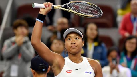 Naomi Osaka raises her racket to celebrate beating Caroline Wozniacki in the China Open semi-finals