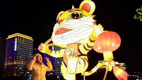 A child interacts with the street lighting of Auspicious Tiger in Hohhot, Inner Mongolia, China.