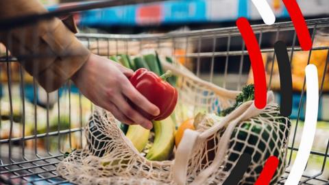 Hand grabbing a pepper from a shopping trolley.