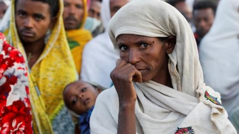 A woman stands in line to receive food donations, at the Tsehaye primary school, which was turned into a temporary shelter for people displaced by conflict, in the town of Shire, Tigray region, Ethiopia, March 15, 2021
