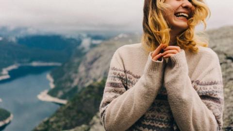 A stock model laughing on the Trolltunga, in Norway