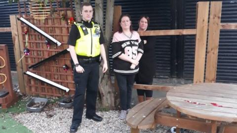 Police officer and volunteers with damaged fence