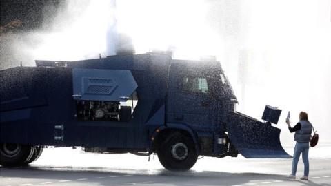 An opposition supporter stands next to a police water cannon truck during a rally to reject the presidential election results in Minsk on 4 October 2020