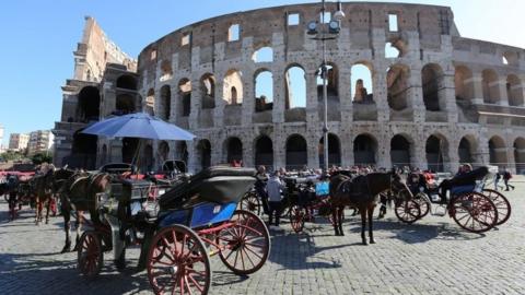 Horse-drawn carriages are seen in front of Rome's ancient Colosseum downtown Rome