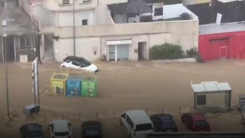 A car floats down a flooded street in Ajaccio, Corsica