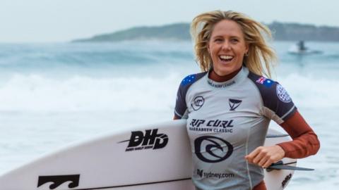 File image of Laura Enever smiling, holding a surfboard