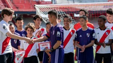 The team shake hands with members of the opposition ahead of a friendly football game.