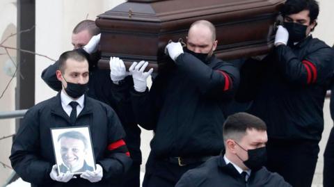 Funeral service workers carry out the coffin of late Russian opposition leader Alexei Navaln