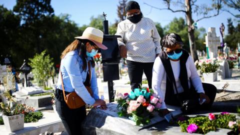 Three women visit a grave in Mexico