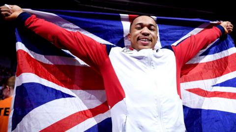 British gymnast Joe Fraser holds up the Union Jack after winning World Championship gold in the men's parallel bars