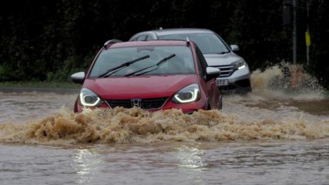 Vehicles are driven through a flooded road