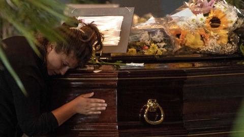 A mourner prays at the coffin of a victim of the Morandi bridge collapse in Genoa, on August 17, 2018.