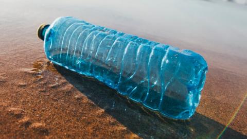 A single discarded plastic water bottle on a sandy beach